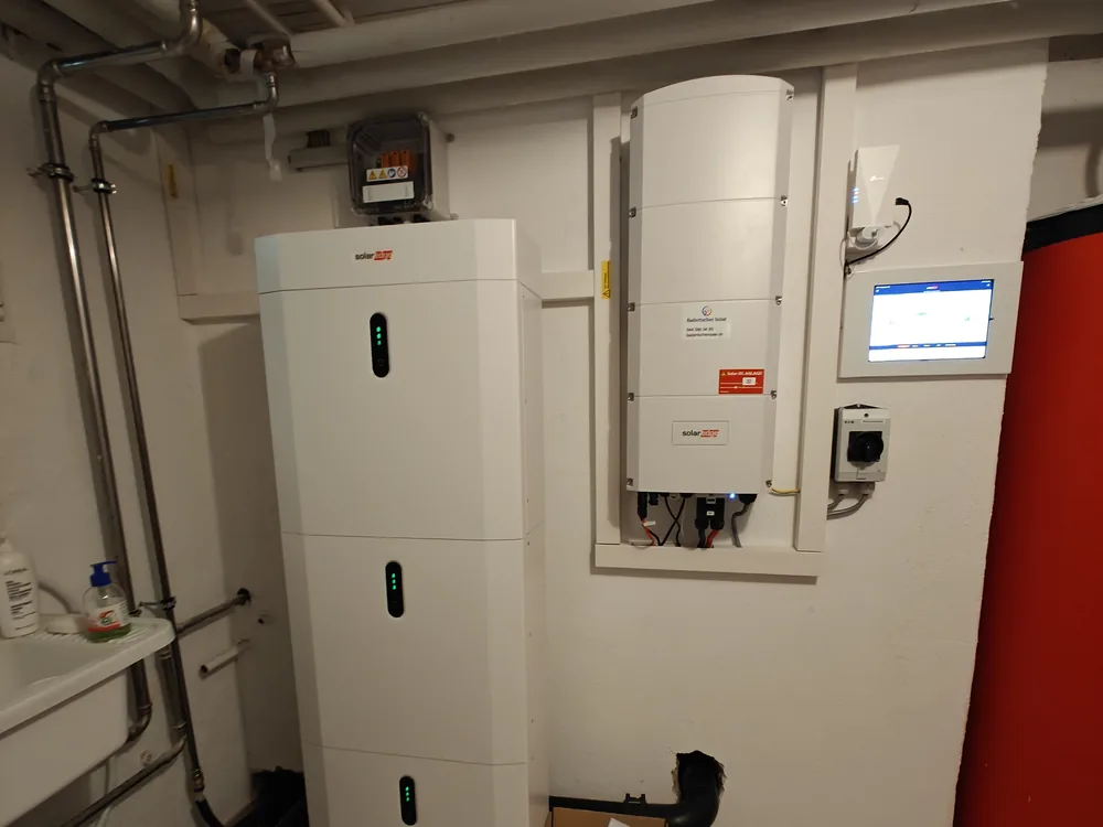 Batteriespeicher mit drei Modulen neben Wechselrichter und Monitoring-Display im Technikraum